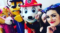 a group of girls posing with a paw patrol mascot